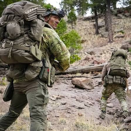 Two soldiers hiking uphill with heavy rucksacks.